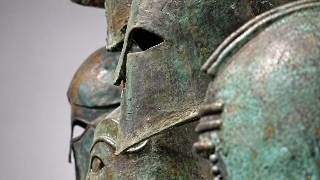 Ancient Greek helmets and historical artworks in the Ancient Symposium art gallery in Athens